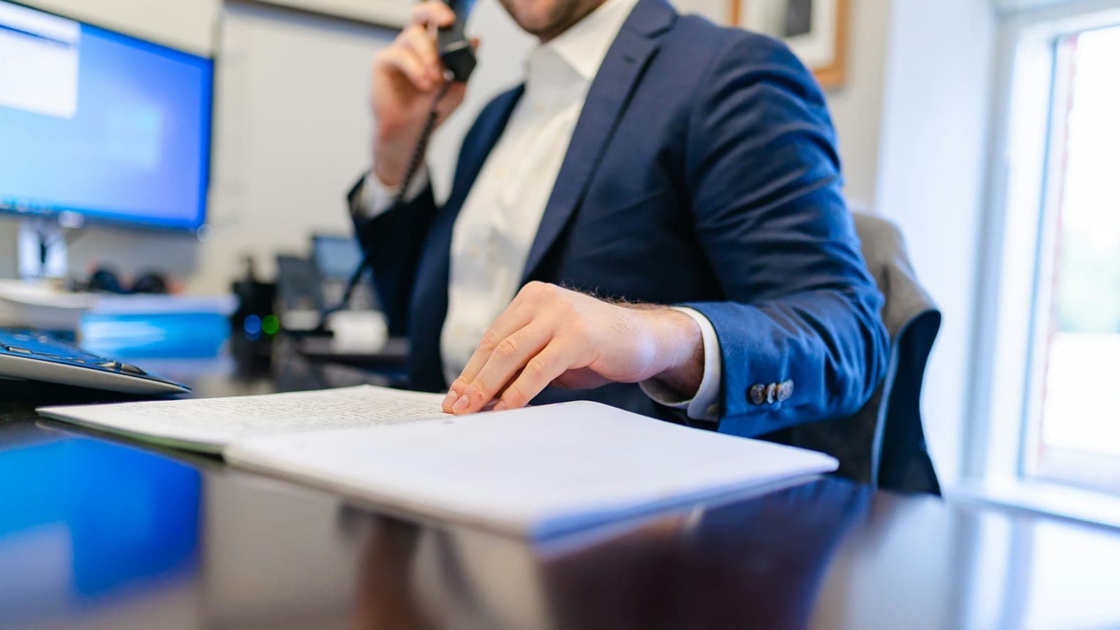 Avocat au téléphone relisant un dossier posé sur son bureau