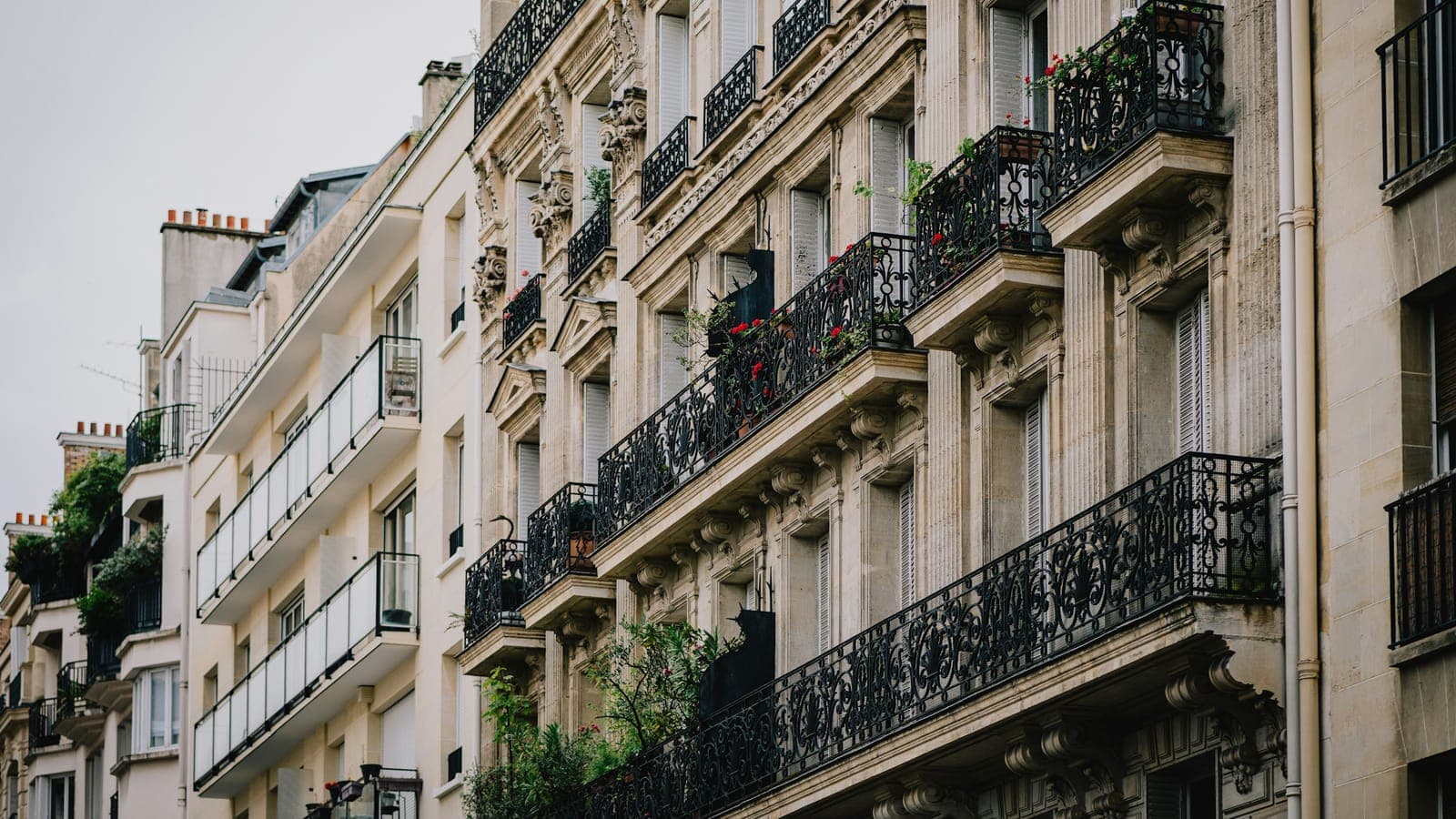 Façades d'immeubles parisiens en pierre de taille avec balcons en fer forgé fleuris