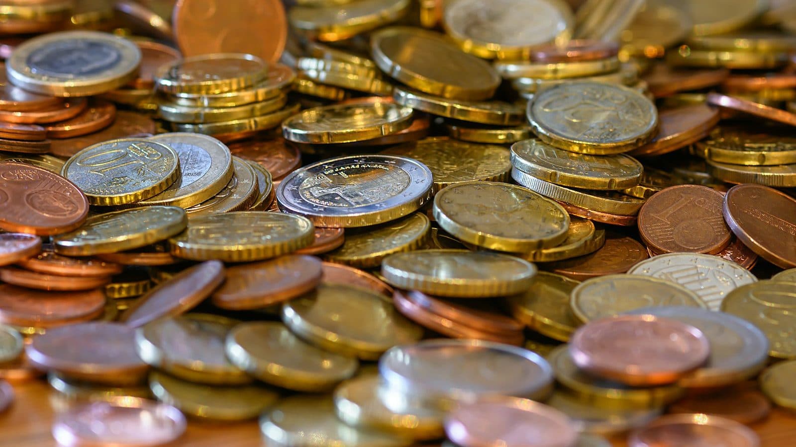 Pièces en euros en gros plan, déversées d'un bocal sur une table en bois