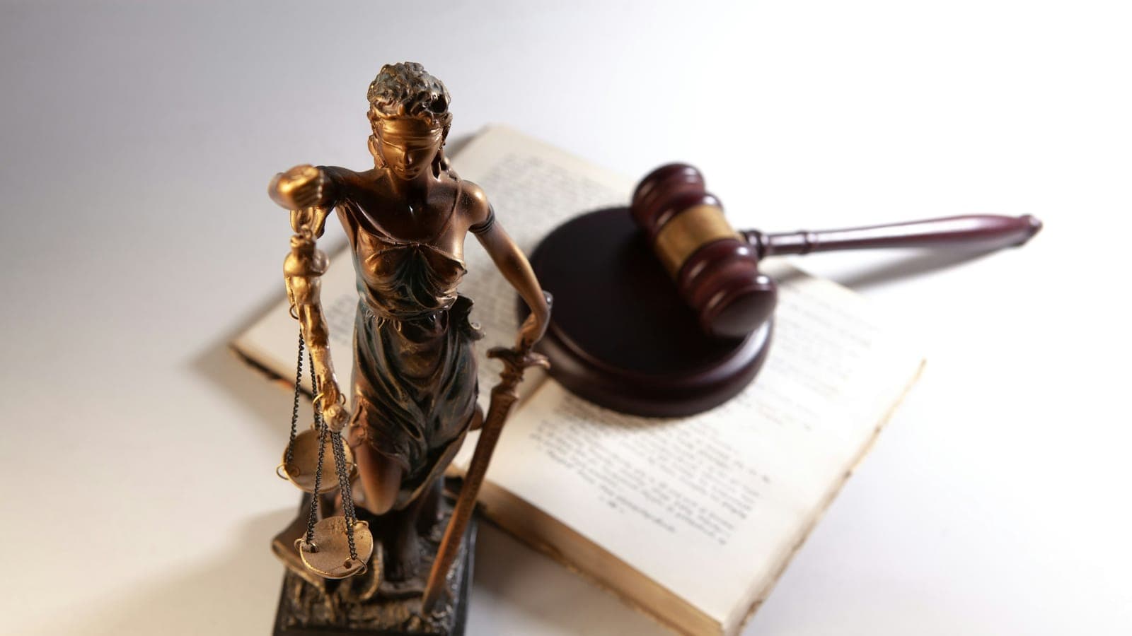 Statuette de la Justice, marteau de juge et livre ouvert posés sur une table