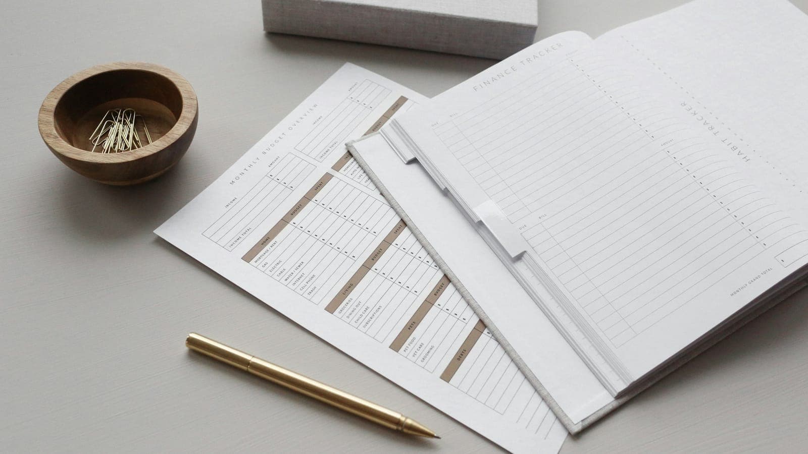 Tableaux financiers imprimés et stylo doré posés sur un bureau gris