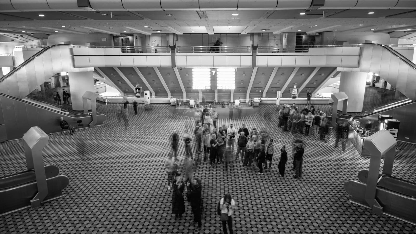 Vue en plongée du hall d'un palais des congrès, visiteurs et escaliers mécaniques
