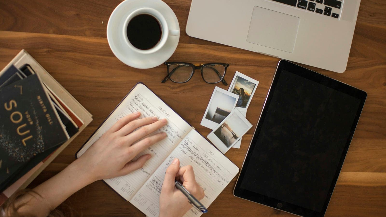 Personne planifiant son projet dans un carnet, à un bureau avec ordinateur et café