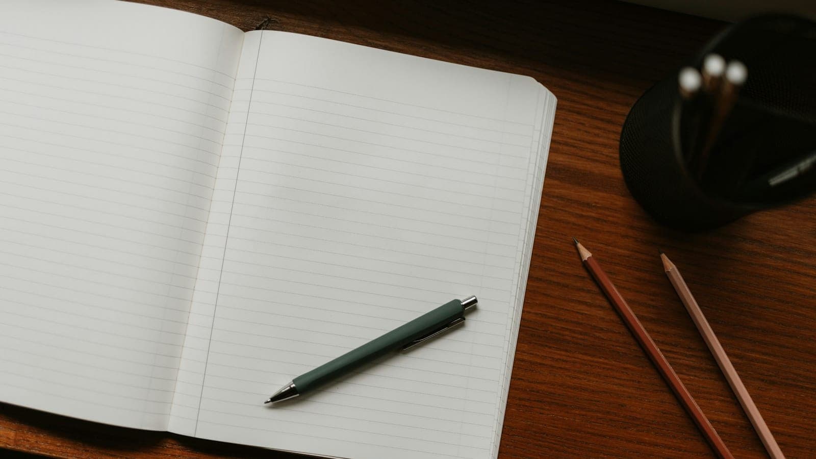 Carnet ouvert, stylo et crayons posés sur un bureau en bois
