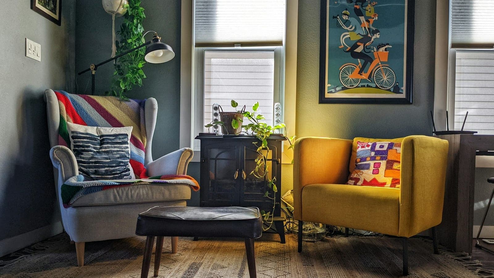 Salon meublé avec deux fauteuils colorés, une table basse et des plantes près de la fenêtre