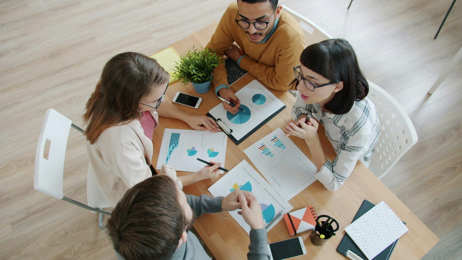 Équipe réunie autour d'une table couverte de graphiques et de tableaux de bord