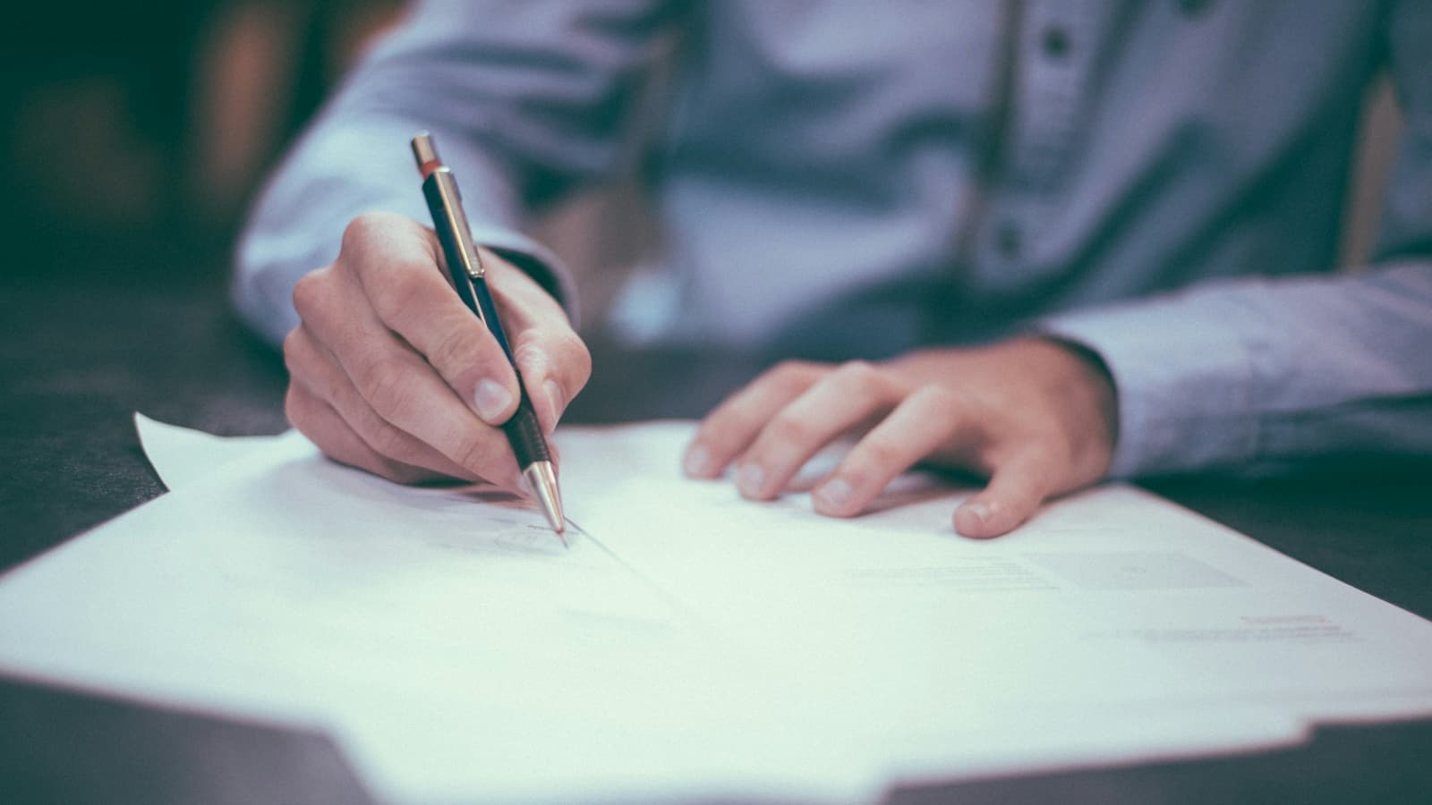 Dirigeant signant des documents au stylo sur un bureau