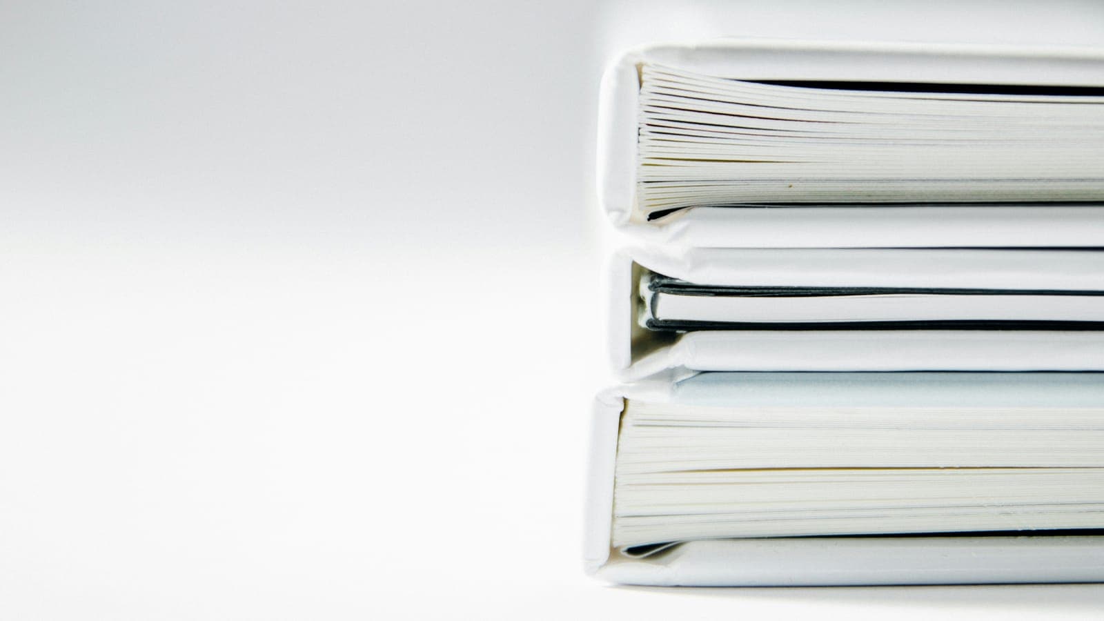 Pile de classeurs blancs posés sur un fond clair