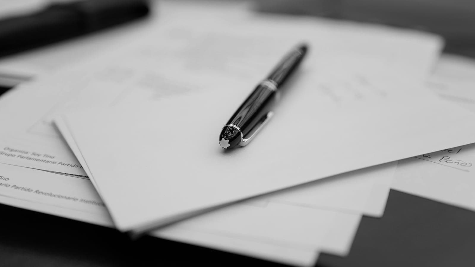 Stylo posé sur une pile de documents imprimés