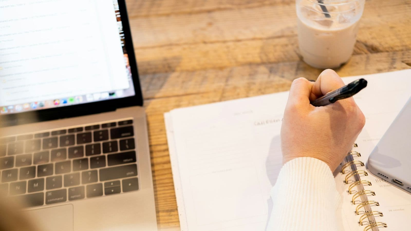 Indépendant prenant des notes dans un carnet à côté de son ordinateur portable