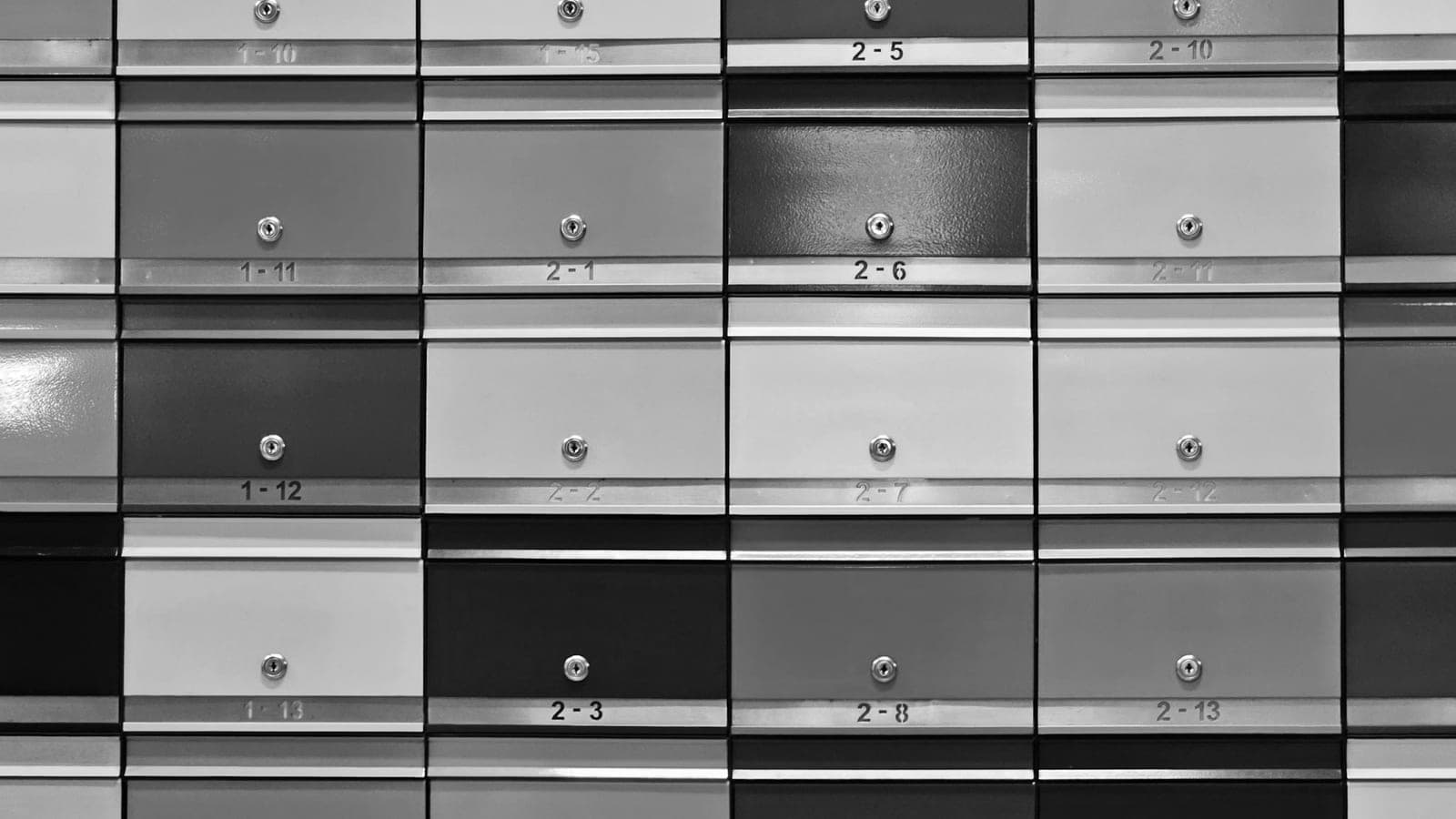 Mur de boîtes aux lettres numérotées, photographié en noir et blanc