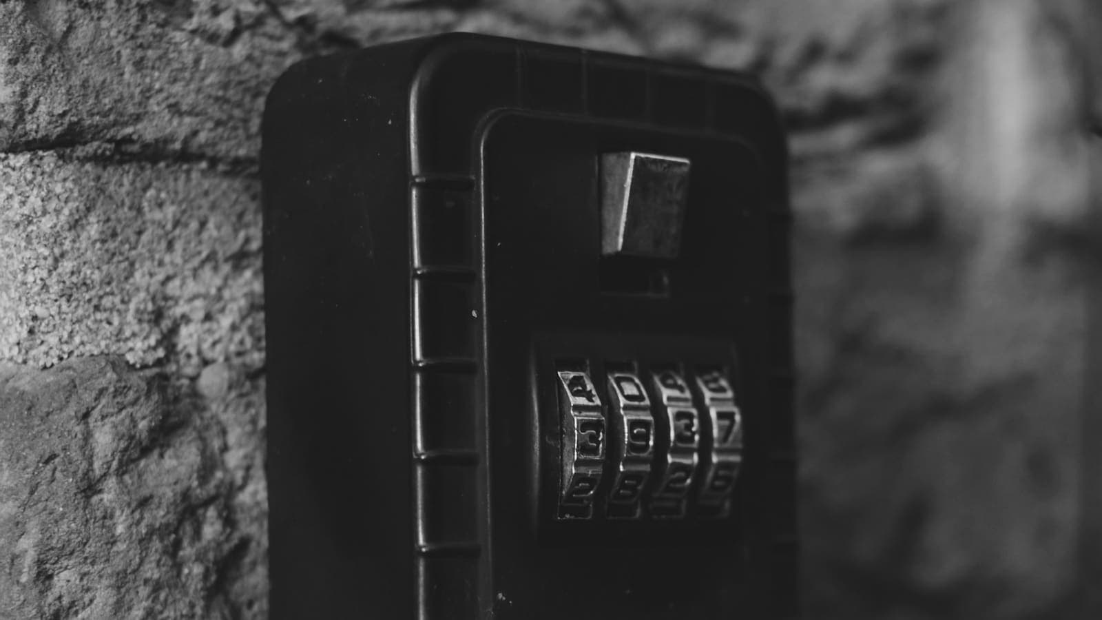 Boîte à clés à code fixée sur un mur en pierre, photo en noir et blanc