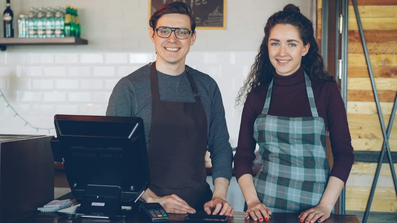 Deux employés en tablier derrière le comptoir d'un café