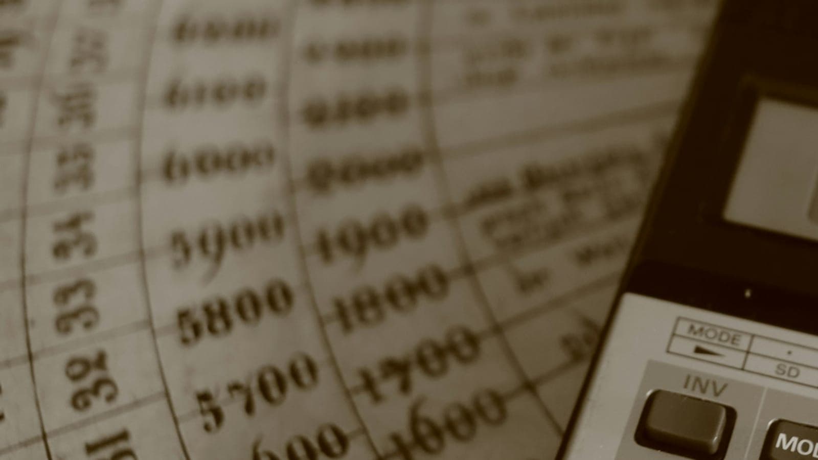 Colonnes de chiffres d'un ancien registre comptable à côté d'une calculatrice