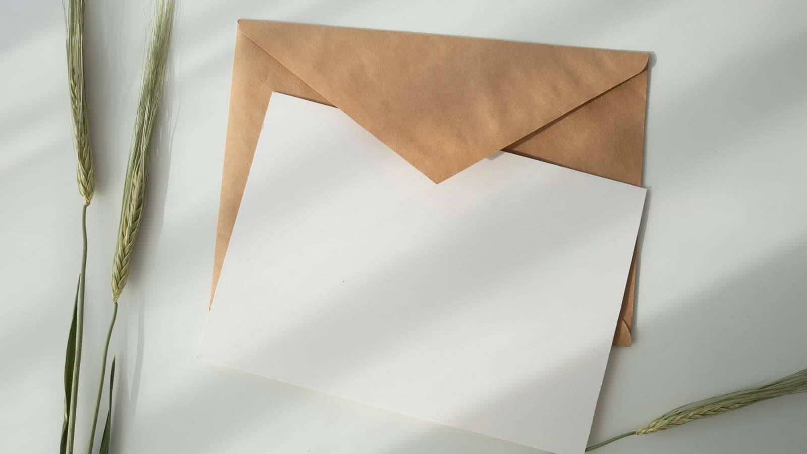 Enveloppe kraft et feuille blanche posées sur un bureau clair
