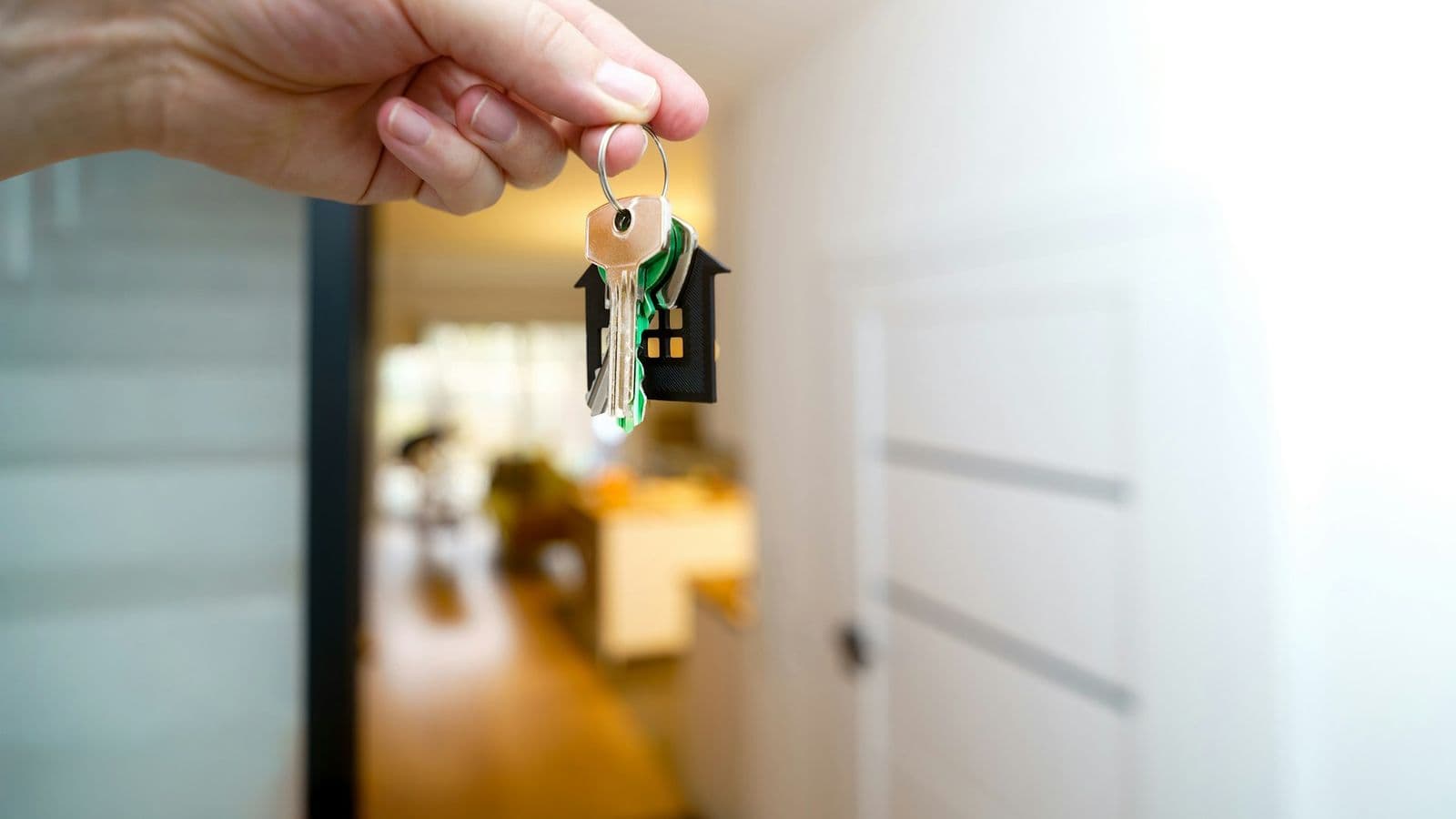 Main tenant les clés d'un appartement avec un porte-clés en forme de maison