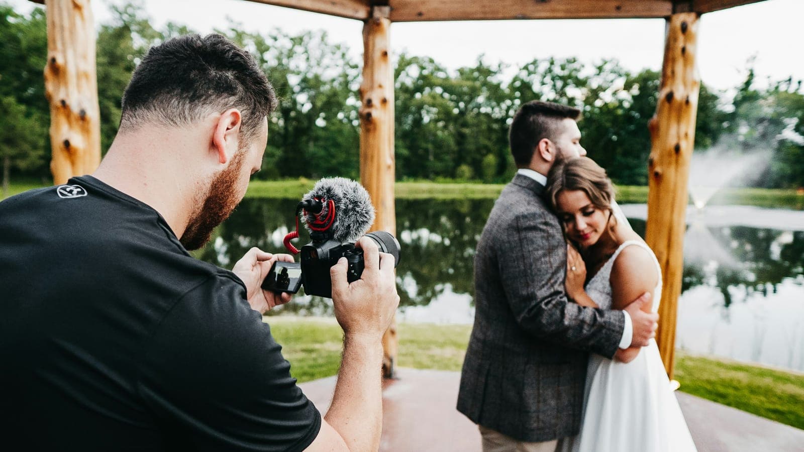 Vidéaste filmant un couple de mariés sous un kiosque en bois, au bord d'un étang